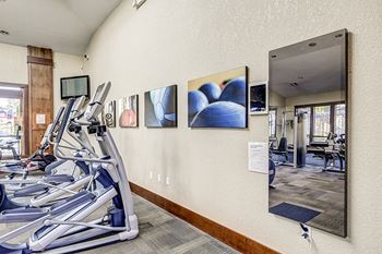 a gym with cardio equipment and mirrors on the wall